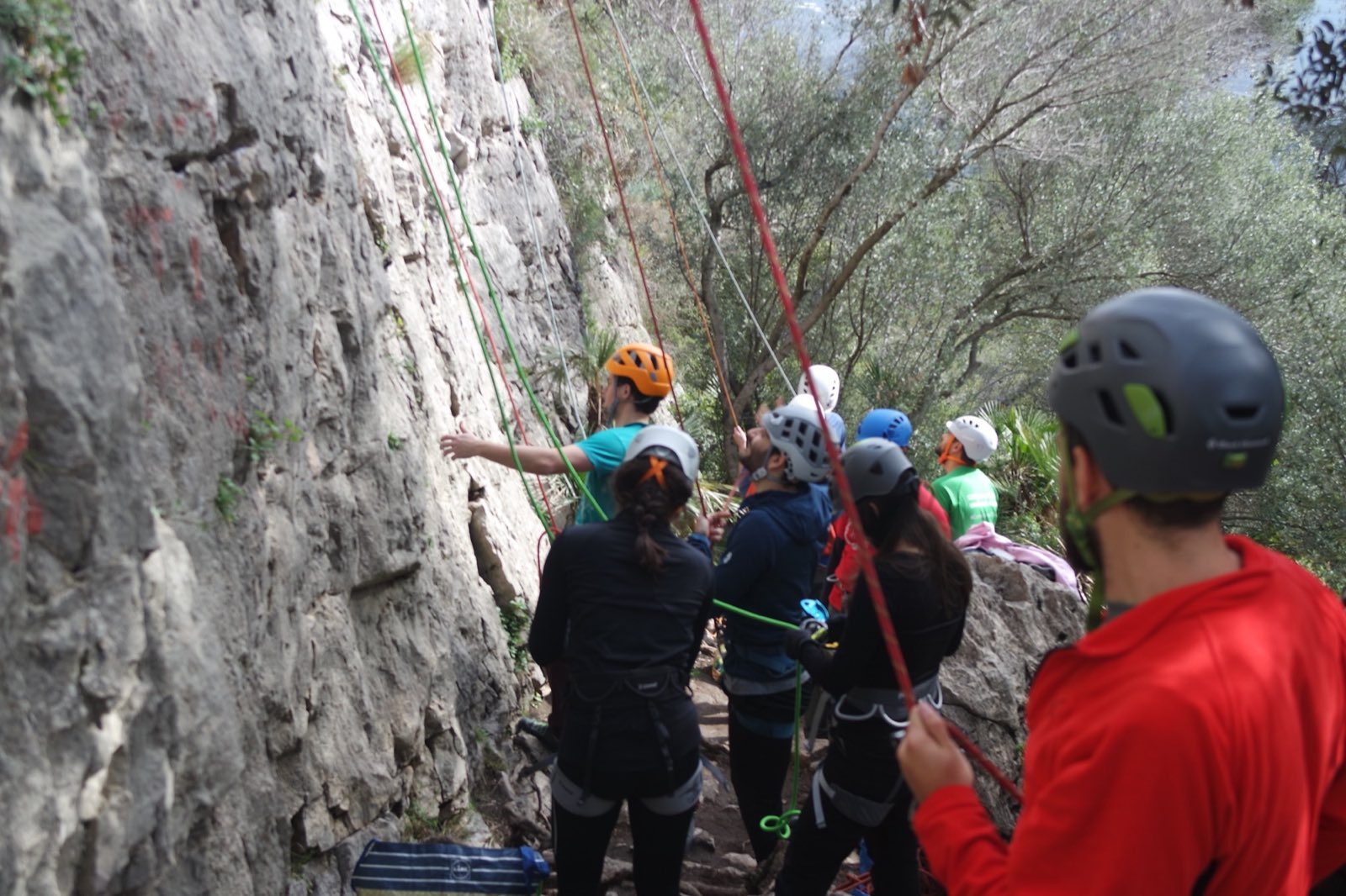 Grupo de escaladores con casco al pie de una vía, montando reuniones